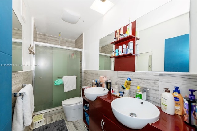 bathroom featuring vanity, a skylight, toilet, tile walls, and an enclosed shower