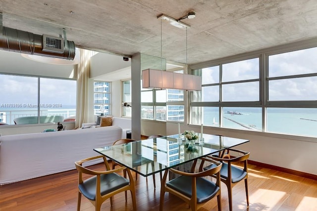 dining room with a wealth of natural light, a water view, and hardwood / wood-style flooring