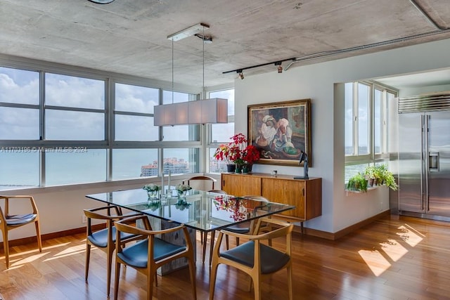 dining area with hardwood / wood-style floors, a water view, and a healthy amount of sunlight