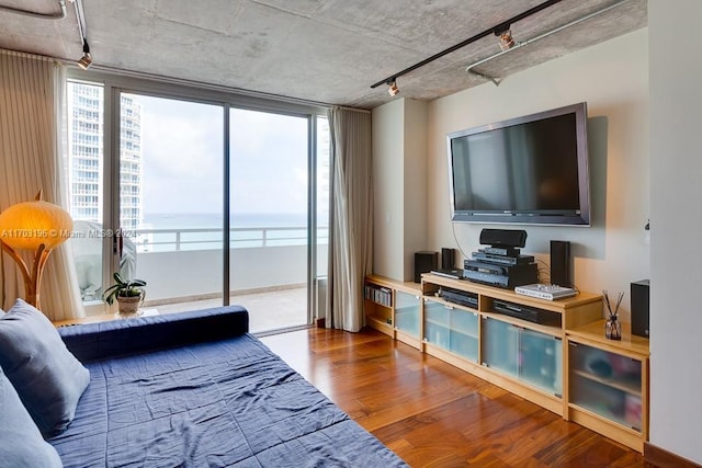 bedroom with track lighting, wood-type flooring, and multiple windows