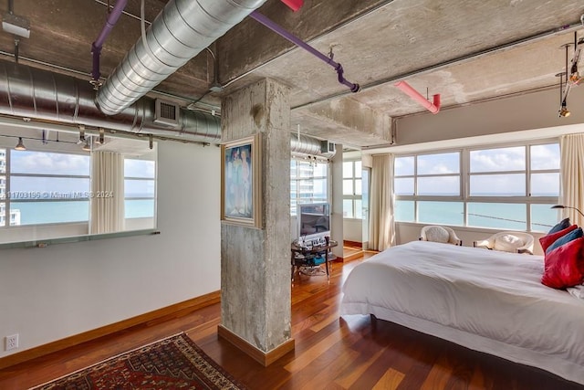 bedroom with a water view and hardwood / wood-style flooring