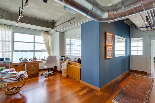 home office with wood-type flooring, built in desk, and a water view