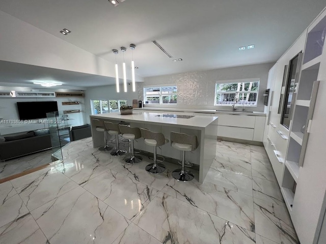 kitchen featuring a kitchen breakfast bar, a large island, white cabinets, and hanging light fixtures