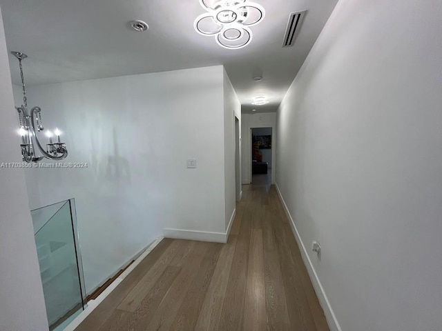 hallway with hardwood / wood-style floors and a chandelier