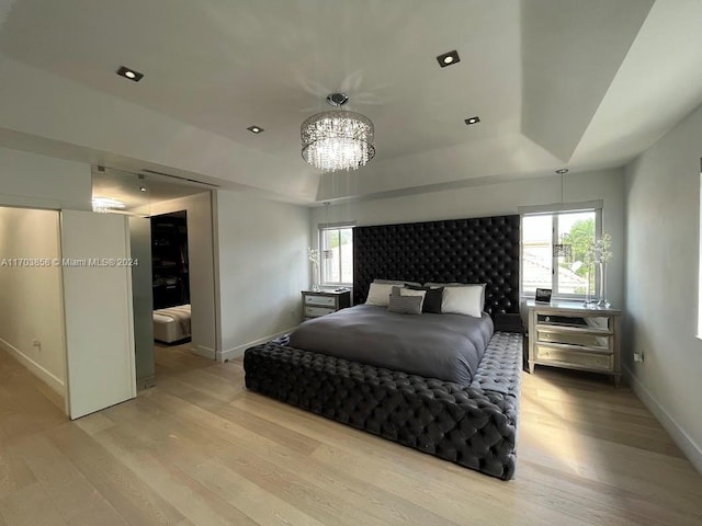 bedroom with light wood-type flooring and a notable chandelier