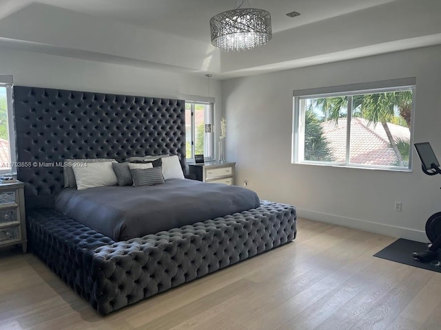 bedroom featuring light hardwood / wood-style flooring, multiple windows, and a notable chandelier