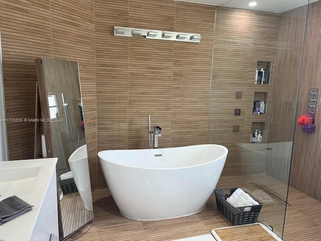 bathroom featuring a bathtub, tile walls, and vanity