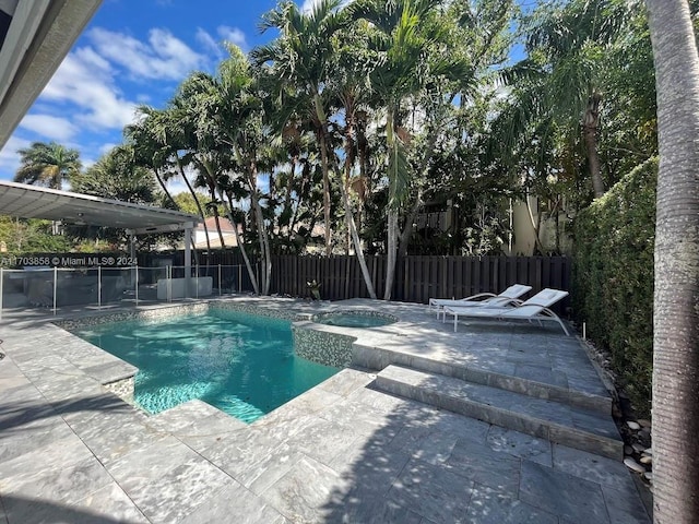 view of swimming pool featuring a patio area and an in ground hot tub