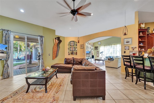 living room with light tile patterned floors, recessed lighting, arched walkways, and ceiling fan