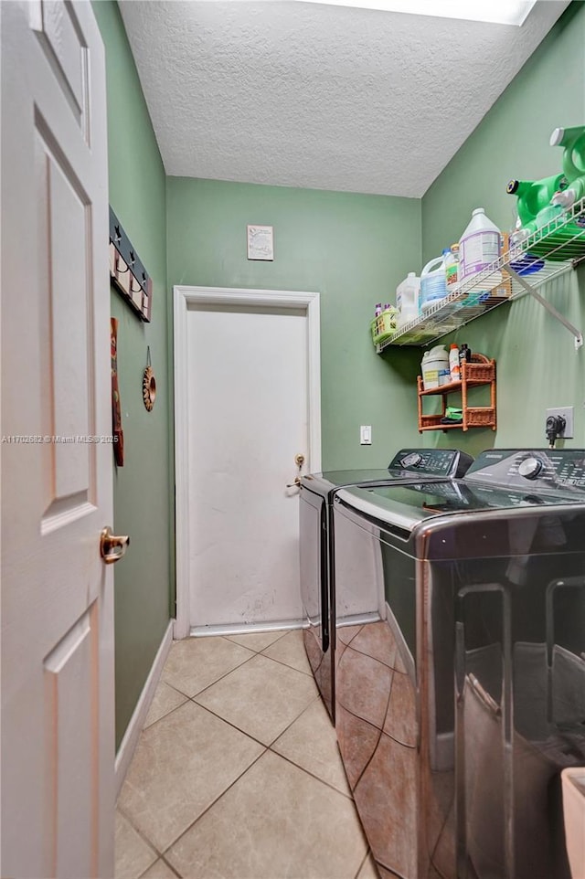 clothes washing area featuring laundry area, light tile patterned floors, independent washer and dryer, and a textured ceiling