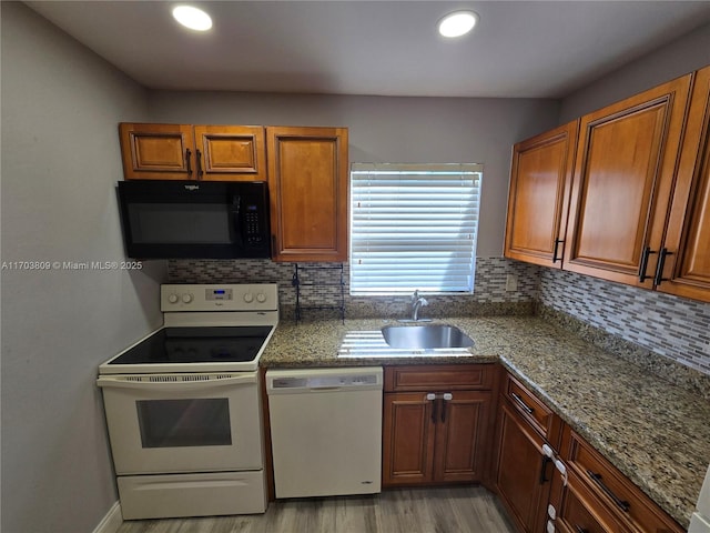 kitchen with decorative backsplash, white appliances, sink, and light hardwood / wood-style flooring