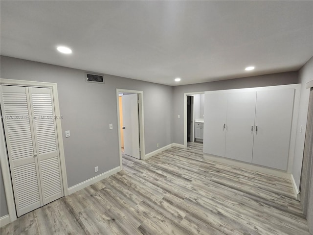 unfurnished bedroom featuring ensuite bathroom and light wood-type flooring