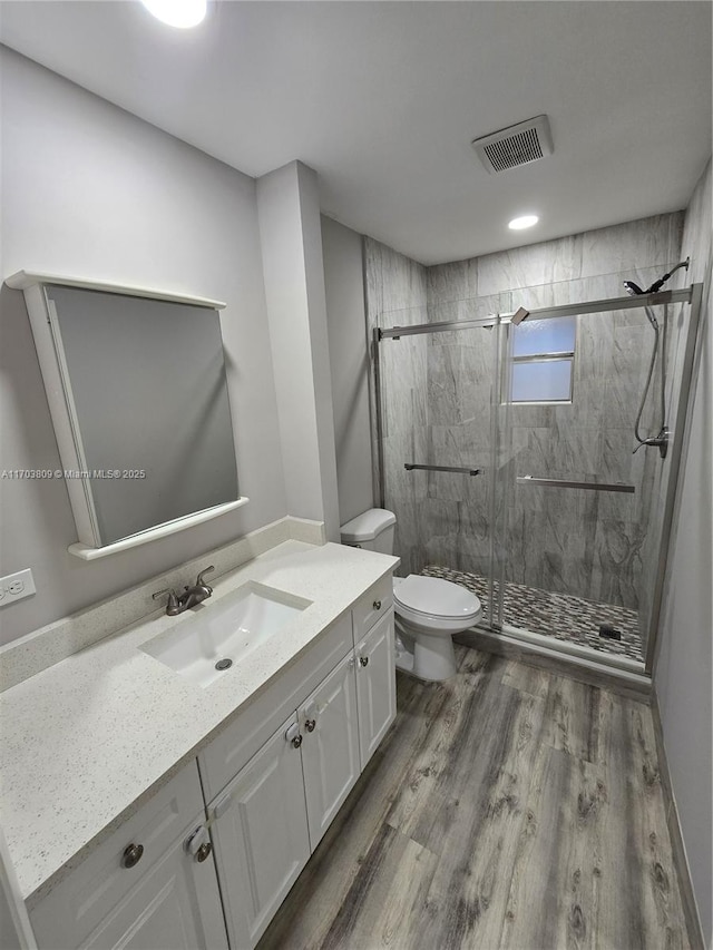 bathroom featuring hardwood / wood-style floors, vanity, toilet, and a shower with door