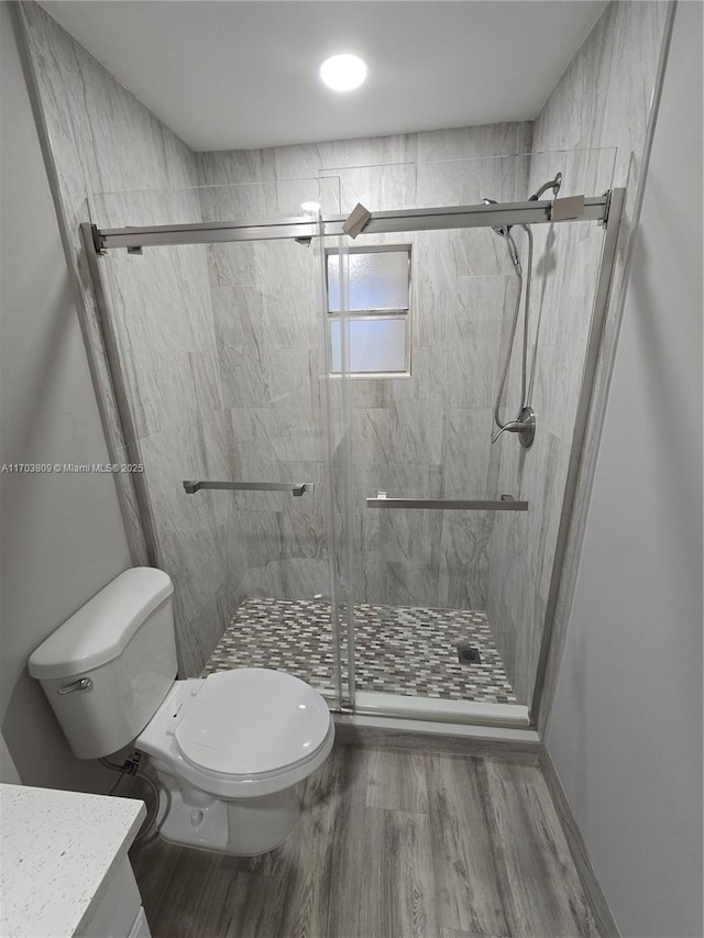 bathroom featuring hardwood / wood-style floors, vanity, toilet, and a shower with door