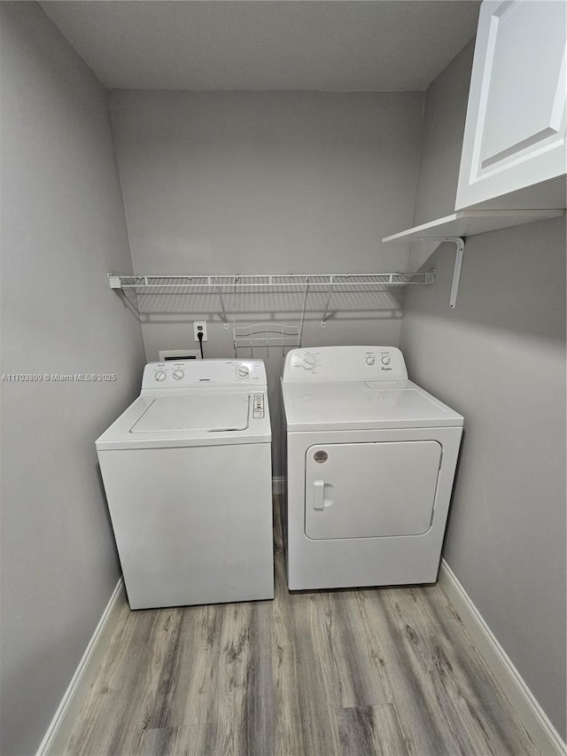 laundry area with light hardwood / wood-style floors, cabinets, and independent washer and dryer