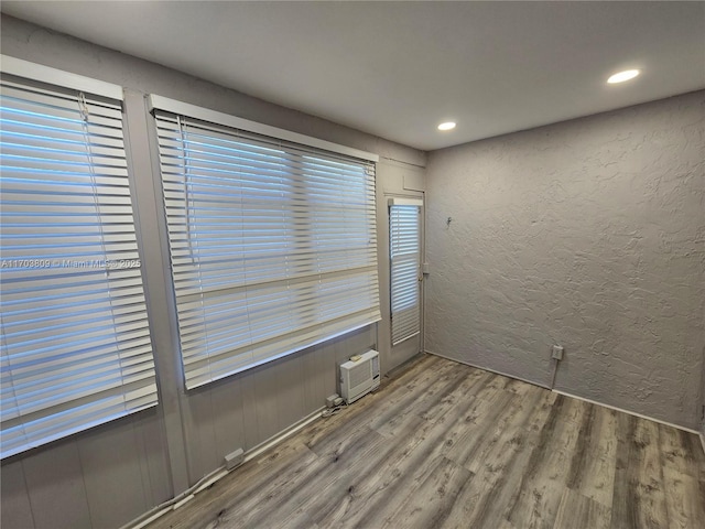 empty room featuring wood-type flooring and a wall mounted air conditioner