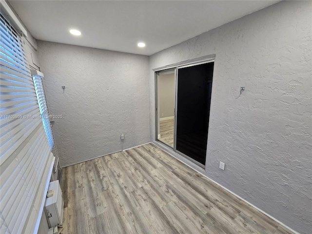 empty room featuring a wall mounted air conditioner and light hardwood / wood-style floors