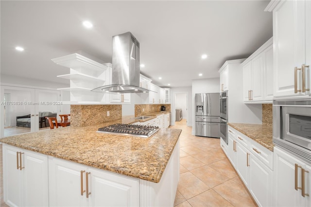 kitchen with white cabinets, wall chimney exhaust hood, light tile patterned floors, light stone countertops, and appliances with stainless steel finishes