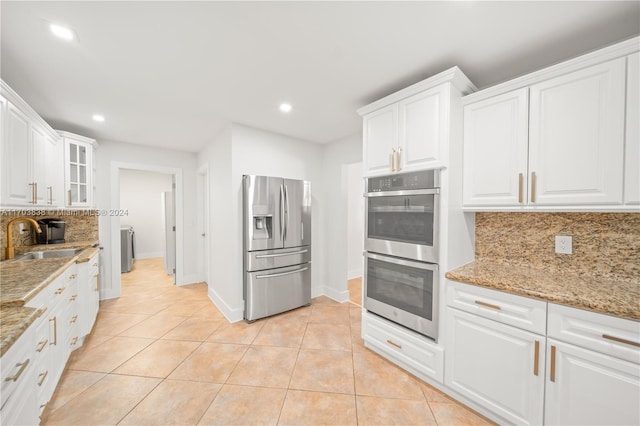 kitchen with sink, light tile patterned floors, decorative backsplash, white cabinets, and appliances with stainless steel finishes