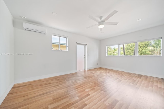 empty room featuring an AC wall unit, light hardwood / wood-style flooring, and a healthy amount of sunlight