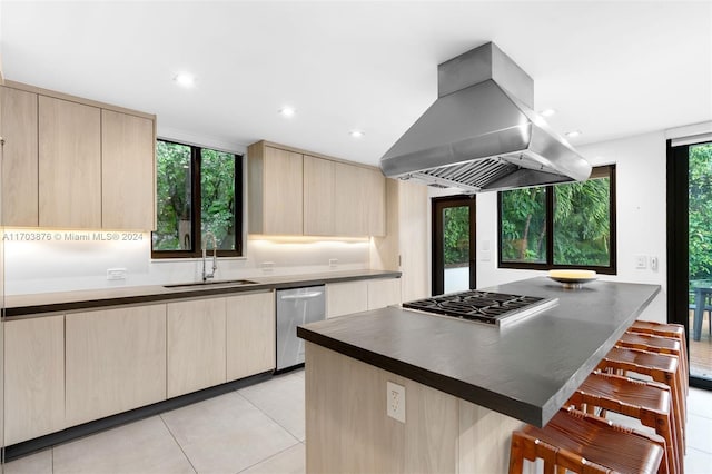 kitchen with island exhaust hood, appliances with stainless steel finishes, a breakfast bar, sink, and a center island