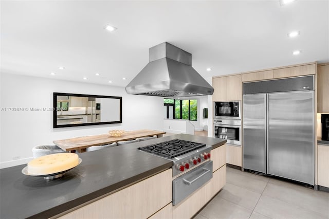 kitchen featuring island exhaust hood, light brown cabinetry, built in appliances, and light tile patterned floors