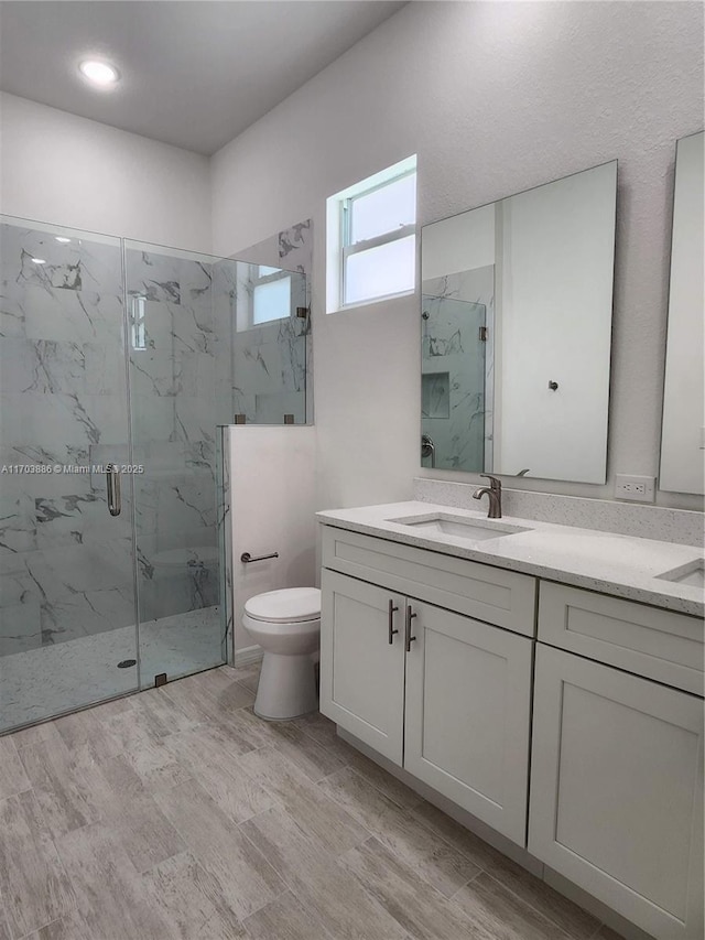 bathroom featuring hardwood / wood-style flooring, vanity, toilet, and a shower with shower door