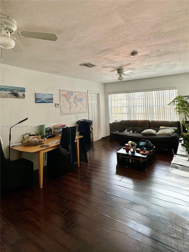 living room with a textured ceiling, dark hardwood / wood-style flooring, and ceiling fan