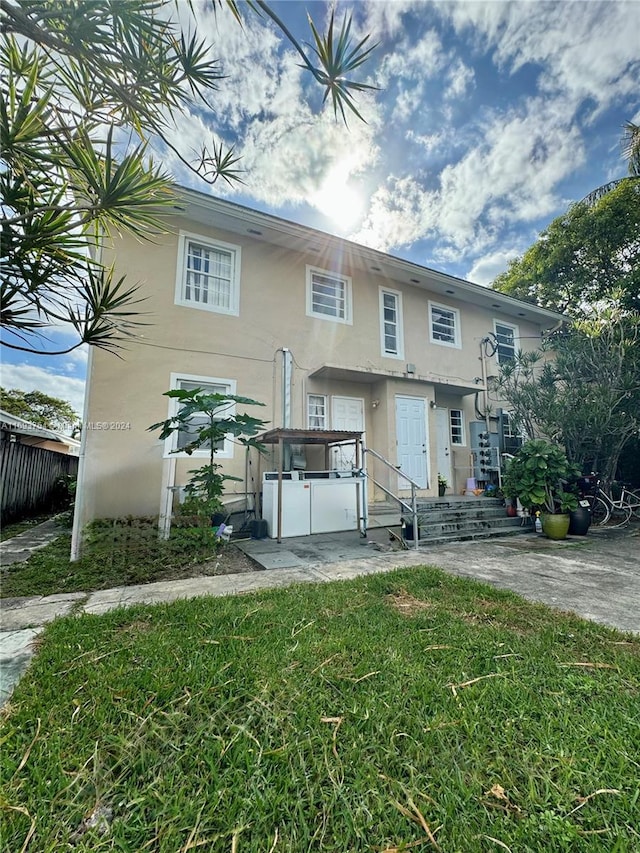 rear view of property with a patio area, a jacuzzi, and a yard