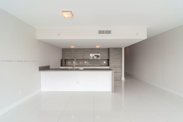 kitchen with kitchen peninsula, sink, and light tile patterned floors