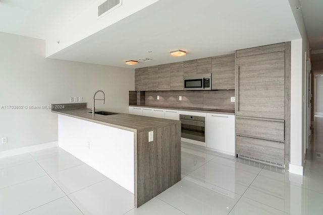 kitchen featuring white cabinets, sink, light tile patterned floors, and stainless steel appliances