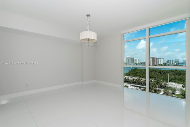 tiled spare room with floor to ceiling windows and a notable chandelier