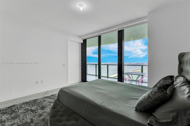 bedroom with access to exterior, a water view, and expansive windows