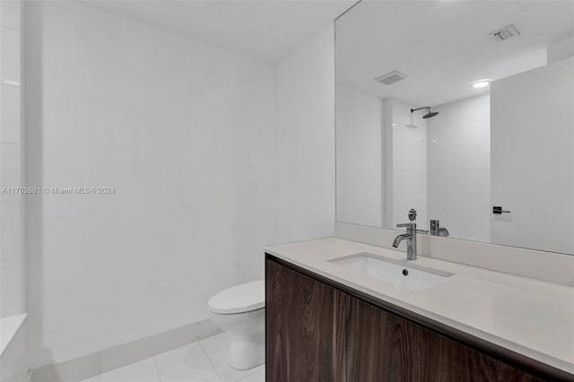 bathroom with tile patterned flooring, vanity, toilet, and a tile shower