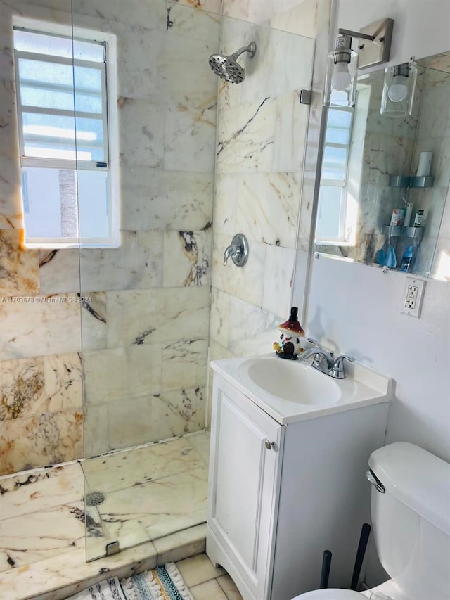 bathroom with toilet, vanity, a healthy amount of sunlight, and tiled shower