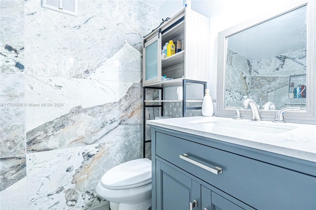 bathroom featuring vanity, tile walls, and toilet