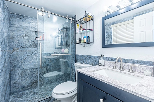 bathroom with a shower with door, vanity, and toilet