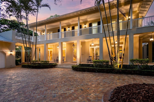 back house at dusk with a balcony