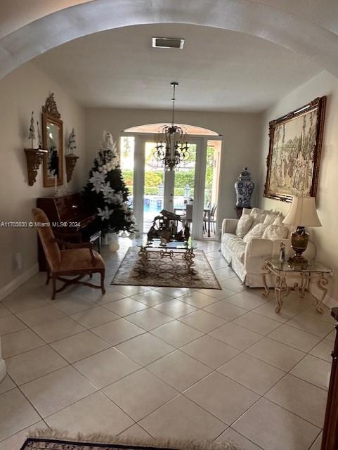 living room with a chandelier, light tile patterned floors, and french doors