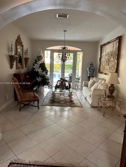 tiled living room featuring french doors and an inviting chandelier