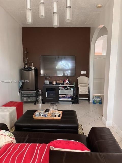 living room featuring gas water heater, tile patterned flooring, and a textured ceiling