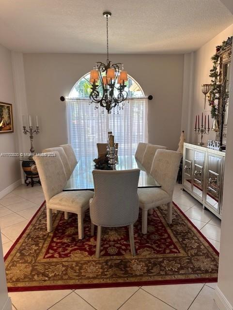 tiled dining room with a textured ceiling and an inviting chandelier