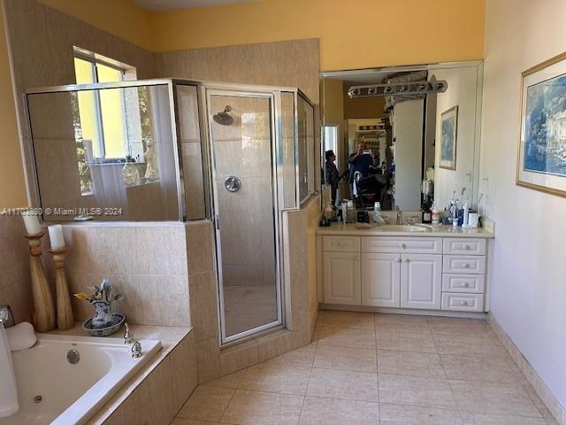 bathroom with tile patterned flooring, vanity, and plus walk in shower