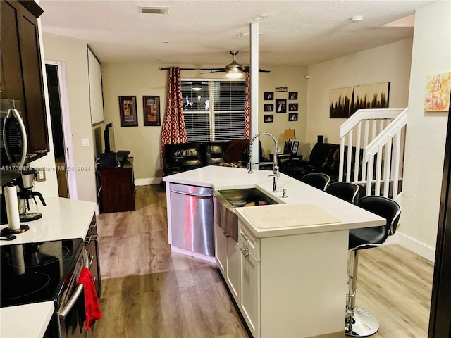 kitchen with a breakfast bar area, light hardwood / wood-style flooring, ceiling fan, an island with sink, and stainless steel appliances