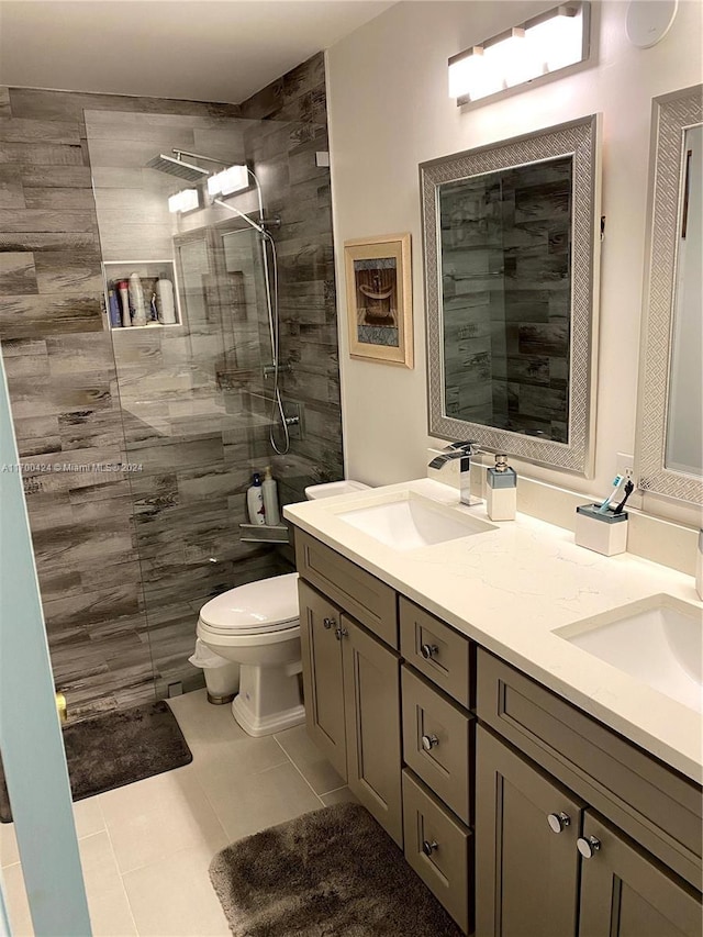 bathroom with tile patterned floors, vanity, toilet, and tiled shower