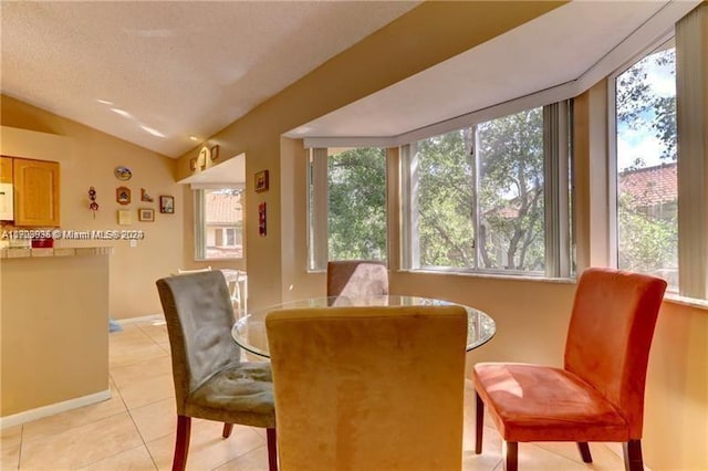 dining area featuring plenty of natural light, lofted ceiling, and light tile patterned floors