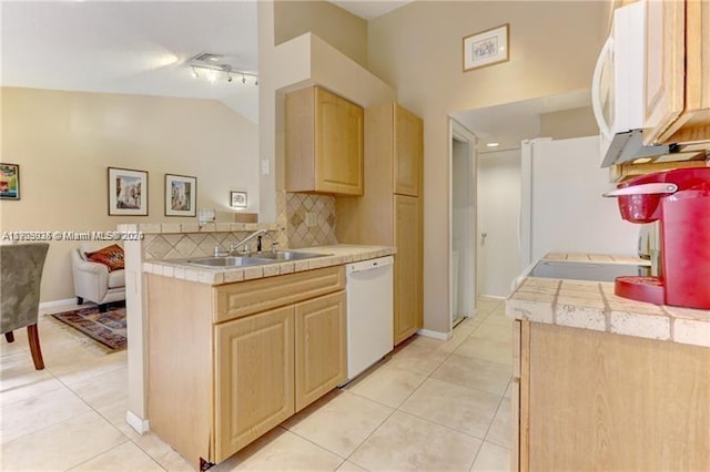 kitchen featuring light brown cabinets, white appliances, and vaulted ceiling