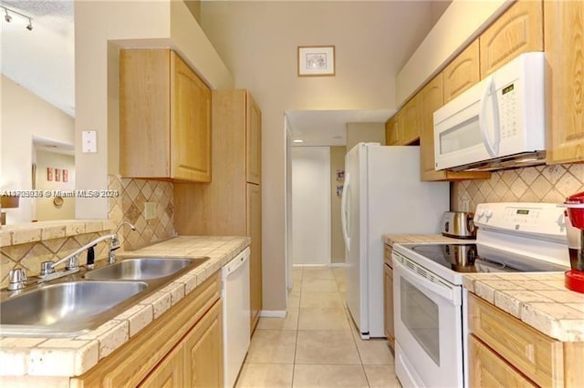 kitchen featuring decorative backsplash, light tile patterned floors, white appliances, and light brown cabinetry