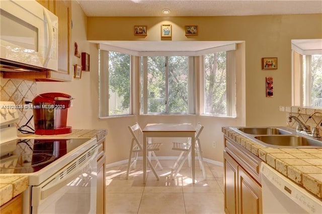 kitchen with plenty of natural light, light tile patterned flooring, white appliances, and sink