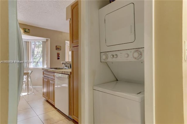 laundry area featuring light tile patterned floors, a textured ceiling, and stacked washer and clothes dryer